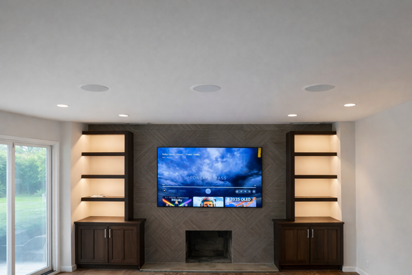 Custom Home Theater Installation - For this project, our team completed a full home theater installation focused on clean integration, hidden wiring, and high-performance audio and video.
The scope of work included mounting a Samsung Frame TV above a tiled fireplace, ensuring precise alignment and a seamless finish. To keep the setup clean and code-compliant, we installed a recessed electrical outlet behind the TV so no wires are visible.
For audio, we installed five in-ceiling surround speakers along with speaker wire runs and concealment throughout the room, carefully routing all wiring inside the walls. We also completed a custom drywall cut-out and installation for an in-wall subwoofer, including precise stud trimming to ensure a perfect fit without compromising the structure.
All AV equipment was provided and  professionally installed and organized inside the custom cabinetry, including a Sony 7.2-channel 8K receiver, Sonos Port streaming component, subwoofer amplifier, and an active cooling fan system to protect the equipment from overheating and extend its lifespan.
Throughout the project, extra care was taken to protect finished surfaces, maintain symmetry with the built-in shelving, and deliver a clean, polished final result. The end outcome is a fully integrated home theater system with powerful sound, a sleek visual appearance, and no exposed cables.
