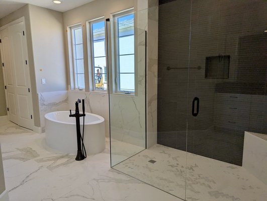 Bathroom at The Reserve at River Oaks - This is a classic primary bathroom with a modern twist that went into one of the models in The Reserve at River Oaks in Paso Robles. Large white marble-like tiles were used throughout, including a shower wall. Black Quartz was used on the vanity and then black tiles again on another shower wall. Bathroom at The Reserve at River Oaks - This is a classic primary bathroom with a modern twist that went into one of the models in The Reserve at River Oaks in Paso Robles. Large white marble-like tiles were used throughout, including a shower wall. Black Quartz was used on the vanity and then black tiles again on another shower wall.