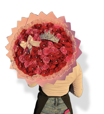 Reina Bouquet - A majestic bouquet of premium red and pink roses, adorned with delicate sparkles, an elegant bow, and a crown that symbolizes royalty and distinction. Wrapped in soft pink tones, it is the perfect gift to make that special someone feel like a true queen on her day.