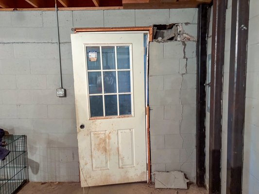 Masonry & Foundation Repair - This customer in Reader, WV, had some severe settlement and movement of a wall in his basement. We removed and replaced a section of the block wall and then performed a concrete retrofit of that wall. We also replaced the lentil and basement door. On the exterior we excavated and installed our helical piling and repaired a broken drain line. Once the stabilization and lift were completed, we backfilled, tuck pointed, and added new seed and straw to the area. Masonry & Foundation Repair - This customer in Reader, WV, had some severe settlement and movement of a wall in his basement. We removed and replaced a section of the block wall and then performed a concrete retrofit of that wall. We also replaced the lentil and basement door. On the exterior we excavated and installed our helical piling and repaired a broken drain line. Once the stabilization and lift were completed, we backfilled, tuck pointed, and added new seed and straw to the area.