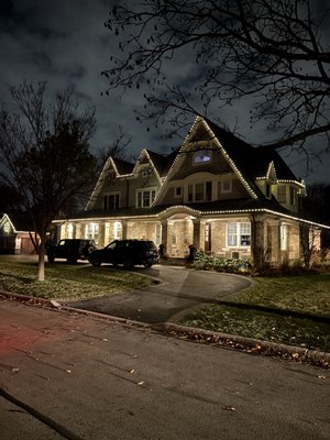 Holiday Lighting - This stunning home features a beautifully clean and classic Christmas light installation that highlights its architectural charm. Warm white LED lights trace every roofline, dormer, and peak, perfectly accentuating the home’s unique design and creating a timeless holiday glow. The gentle illumination along the eaves and windows adds a touch of sophistication, while the subtle lighting on the landscaping brings balance and warmth to the overall look.
Our team specializes in creating elegant, professional lighting designs like this one—where every bulb is perfectly aligned, and every detail shines. Whether you prefer a cozy, classic look or something bold and festive, we’ll transform your home into a holiday masterpiece. Holiday Lighting - This stunning home features a beautifully clean and classic Christmas light installation that highlights its architectural charm. Warm white LED lights trace every roofline, dormer, and peak, perfectly accentuating the home’s unique design and creating a timeless holiday glow. The gentle illumination along the eaves and windows adds a touch of sophistication, while the subtle lighting on the landscaping brings balance and warmth to the overall look.
Our team specializes in creating elegant, professional lighting designs like this one—where every bulb is perfectly aligned, and every detail shines. Whether you prefer a cozy, classic look or something bold and festive, we’ll transform your home into a holiday masterpiece.