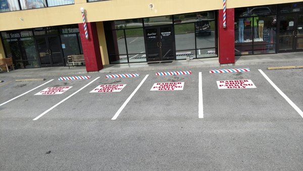 Barbershop Parking Lot Stenciling - We painted 4 parking spots for Buzzed & Faded in Branson, MO. 
The main stripes were painted white, and the parking blocks were painted to match the barbershop poles hanging outside. Inside each parking spot, we stenciled in clear and bold red lettering that read "Barber Shop Parking Only" over a white background.