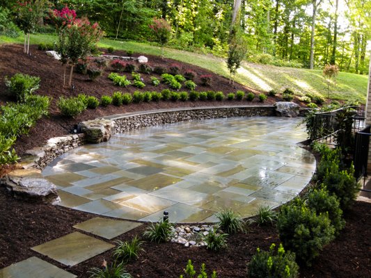 Patios - Custom Stonescaping can install both “dry set” or “wet set” patios. Dry set or dry laid patios require a gravel base for drainage, and either a stone dust or sand layer to help ensure the top stones or pavers are level. The joints are then filled with stone dust, sand, pea gravel, or polymeric sand. Wet set or veneered patios require a concrete slab base over gravel with wire mesh and or rebar in the concrete first. Stone can then be mortared or veneered onto the concrete base. The joints are then filled solid with mortar. Custom Stonescaping can build any size or shape patio. Often times on organic free flowing shape is preferred and can be cut into whatever shape the client chooses at no additional cost. Both dry set and wet set patios have advantages and disadvantages depending on the location and the application. Contact us to come out for a free site visit to help you decide what patio is right for you.
Call for a Free Estimate: 703-407-8663 Patios - Custom Stonescaping can install both “dry set” or “wet set” patios. Dry set or dry laid patios require a gravel base for drainage, and either a stone dust or sand layer to help ensure the top stones or pavers are level. The joints are then filled with stone dust, sand, pea gravel, or polymeric sand. Wet set or veneered patios require a concrete slab base over gravel with wire mesh and or rebar in the concrete first. Stone can then be mortared or veneered onto the concrete base. The joints are then filled solid with mortar. Custom Stonescaping can build any size or shape patio. Often times on organic free flowing shape is preferred and can be cut into whatever shape the client chooses at no additional cost. Both dry set and wet set patios have advantages and disadvantages depending on the location and the application. Contact us to come out for a free site visit to help you decide what patio is right for you.
Call for a Free Estimate: 703-407-8663