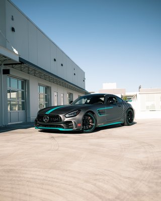 Mercedes AMG GTR - Full Custom Designed Wrap - For the 2022 Luxury & Supercar Weekend, we came up with the Bottas Edition inspired livery for this Mercedes AMG GTR.
Designed and created in house, the project started from body measurements for the design to be created in collaboration with OCHK Media. Utilizing a Satin Dark Grey base wrap, Mercedes AMG Stars were placed on the rear quarter panels, with Petronas Teal accenting, and stripes all over the vehicle, including the fenders, sideskirts, hood, and wing tips. In addition to a full colour change, the wheels were repainted from silver to Black/Petronas Teal.
Revealed at Luxury & Supercar Weekend, this design won the award Top Racing Livery. Check out the photos below to see the immense detail of this project. Mercedes AMG GTR - Full Custom Designed Wrap - For the 2022 Luxury & Supercar Weekend, we came up with the Bottas Edition inspired livery for this Mercedes AMG GTR.
Designed and created in house, the project started from body measurements for the design to be created in collaboration with OCHK Media. Utilizing a Satin Dark Grey base wrap, Mercedes AMG Stars were placed on the rear quarter panels, with Petronas Teal accenting, and stripes all over the vehicle, including the fenders, sideskirts, hood, and wing tips. In addition to a full colour change, the wheels were repainted from silver to Black/Petronas Teal.
Revealed at Luxury & Supercar Weekend, this design won the award Top Racing Livery. Check out the photos below to see the immense detail of this project.
