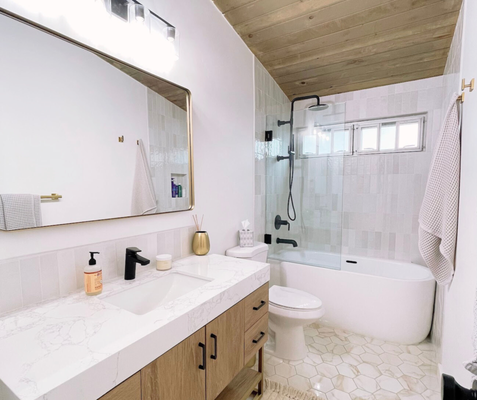 A Clean, Elevated Bathroom Renovation - This bathroom remodel was all about creating a clean, modern space while keeping it warm and inviting. We fully updated the layout with a focus on functionality, quality materials, and timeless design details that will last for years. The vanity features custom wood cabinetry paired with a sleek quartz countertop and an integrated sink for a seamless, modern look. Matte black fixtures were installed throughout to add contrast and give the space a bold, updated feel. The mirror and lighting were carefully selected to enhance brightness while keeping the design simple and uncluttered. In the shower and tub area, we installed new tile with a clean, uniform layout and finished it with a glass enclosure to keep the space open and airy. The wood plank ceiling adds warmth and character, tying the entire bathroom together and elevating the overall design. New flooring was installed to complete the remodel, providing both durability and a clean aesthetic. From demolition to final details, our team handled every step with care, clear communication, and attention to detail. This project is a great example of how thoughtful design and quality craftsmanship can completely transform a bathroom. If you’re considering a bathroom remodel, we’d be happy to help bring your vision to life. A Clean, Elevated Bathroom Renovation - This bathroom remodel was all about creating a clean, modern space while keeping it warm and inviting. We fully updated the layout with a focus on functionality, quality materials, and timeless design details that will last for years. The vanity features custom wood cabinetry paired with a sleek quartz countertop and an integrated sink for a seamless, modern look. Matte black fixtures were installed throughout to add contrast and give the space a bold, updated feel. The mirror and lighting were carefully selected to enhance brightness while keeping the design simple and uncluttered. In the shower and tub area, we installed new tile with a clean, uniform layout and finished it with a glass enclosure to keep the space open and airy. The wood plank ceiling adds warmth and character, tying the entire bathroom together and elevating the overall design. New flooring was installed to complete the remodel, providing both durability and a clean aesthetic. From demolition to final details, our team handled every step with care, clear communication, and attention to detail. This project is a great example of how thoughtful design and quality craftsmanship can completely transform a bathroom. If you’re considering a bathroom remodel, we’d be happy to help bring your vision to life.
