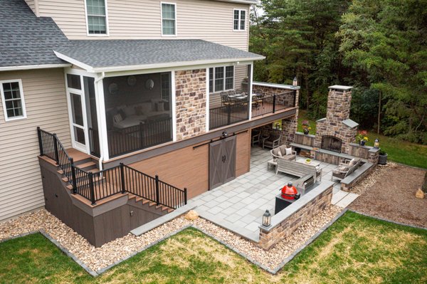 Deck, Screened in Porch, and Patio in Mechanicsburg, PA - We recently completed this farmhouse style deck, featuring Azek Vintage Collection, color English Walnut, decking and Black American Series aluminum railing. The screened in porch highlights a Special Walnut stained choice knotty-pine tongue and groove bead board ceiling. We installed a single power screen to create a seamless walkway from the indoor lounge area into the outdoor dining area. We also built custom made sliding barn doors to conceal the storage area the customer had requested. The patio area (not included in overall price, approx. $125,000-150,000) has an outdoor kitchen, fireplace, and a small hangout corner making it a perfect entrainment area. Deck, Screened in Porch, and Patio in Mechanicsburg, PA - We recently completed this farmhouse style deck, featuring Azek Vintage Collection, color English Walnut, decking and Black American Series aluminum railing. The screened in porch highlights a Special Walnut stained choice knotty-pine tongue and groove bead board ceiling. We installed a single power screen to create a seamless walkway from the indoor lounge area into the outdoor dining area. We also built custom made sliding barn doors to conceal the storage area the customer had requested. The patio area (not included in overall price, approx. $125,000-150,000) has an outdoor kitchen, fireplace, and a small hangout corner making it a perfect entrainment area.