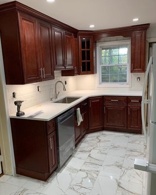 Cherry Wood Set with White Countertops - Finished in 2022, the customer wanted a traditional set with solid wood cabinets and porcelain tile flooring. A wood valance was installed above the window to complete the look. Cherry Wood Set with White Countertops - Finished in 2022, the customer wanted a traditional set with solid wood cabinets and porcelain tile flooring. A wood valance was installed above the window to complete the look.