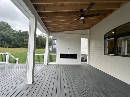 Deck and Porch with Motorized Screens - This project was done on a new build in Aldie, VA. A brand new Trex Enhance deck was built in the color "Foggy Wharf" with Trex Transcends railings in white with black round aluminum pickets and a Trex cap rail to match. The new porch has a shed style roof with T-111 exposed plywood ceiling, electric fireplace built in, ceiling fan, outlets, and two motorized screens along the front. The exterior of the porch has siding to match the house, and the entire deck and porch got a full PVC trim wrap, including the lower support posts and beam.