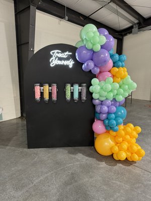 Treat Yourself Wall - If you're looking to create a vibrant and fun atmosphere at your parties and events, look no further than our Candy Wall with a neon sign. This eye-catching and colorful display is sure to be a hit with guests of all ages. The Candy Wall is adorned with a balloon garland of your choice, allowing you to customize the look to match your theme or color scheme. Whether you're hosting a birthday party, wedding reception, or corporate event, this Candy Wall will add a touch of sweetness and excitement to any occasion. So go ahead and indulge your guests' sweet tooth while creating lasting memories with our Candy Wall and neon sign. This price includes set up, delivery and pick up within a 20 mile radius. (will travel further for additional travel Fee) Add it on to any other rental for a $50 discount! Treat Yourself Wall - If you're looking to create a vibrant and fun atmosphere at your parties and events, look no further than our Candy Wall with a neon sign. This eye-catching and colorful display is sure to be a hit with guests of all ages. The Candy Wall is adorned with a balloon garland of your choice, allowing you to customize the look to match your theme or color scheme. Whether you're hosting a birthday party, wedding reception, or corporate event, this Candy Wall will add a touch of sweetness and excitement to any occasion. So go ahead and indulge your guests' sweet tooth while creating lasting memories with our Candy Wall and neon sign. This price includes set up, delivery and pick up within a 20 mile radius. (will travel further for additional travel Fee) Add it on to any other rental for a $50 discount!