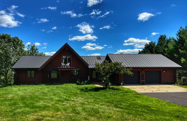 Log Home done in 2022 - This black standing seam roof was installed over a layer of shingles. We were able to do so by installing an underlayment to provide a vapor barrier and cushioning to avoid buckles and oil-panning in the metal.