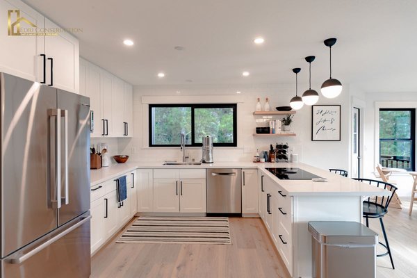 Kitchen Remodel Mill Valley - This remodel transforms the kitchen into a bright, modern, and functional space that balances style with everyday comfort. The U-shaped layout creates an efficient flow for cooking, prep, and entertaining, while crisp white cabinetry with sleek black hardware gives the room a timeless yet contemporary appeal. A clean subway tile backsplash reinforces the fresh design, and open shelving adds character by blending storage with display for decor, cookbooks, or everyday essentials.
At the center of the space, the large kitchen island serves as both a practical workspace and a social hub. Featuring a built-in induction cooktop and an extended quartz countertop, it provides plenty of room for meal prep while doubling as a casual seating area. Modern pendant lights above the island not only brighten the room but also act as striking design elements that tie the space together.
Stainless steel appliances, including a refrigerator, dishwasher, and double wall ovens, bring durability and sophistication, while a built-in coffee station adds a touch of daily luxury. Every detail, from the under-mounted sink framed by a wide black-trimmed window to the subtle recessed lighting, is thoughtfully chosen to create a cohesive and inviting atmosphere.
Extending from the kitchen, the remodel includes a cozy breakfast nook framed by a trio of large windows that bathe the area in natural light. A round dining table and woven pendant fixture make the corner both warm and stylish, creating the perfect spot to enjoy meals with family. Sliding glass doors lead directly to a deck with scenic hillside views, blending indoor comfort with outdoor living.
Light-toned hardwood flooring runs throughout, adding warmth that contrasts beautifully with the white cabinetry and enhancing the open, airy feel. The result is a space that combines practicality with modern elegance, offering a kitchen that is not only visually stunning but also perfectly suited to daily living. Kitchen Remodel Mill Valley - This remodel transforms the kitchen into a bright, modern, and functional space that balances style with everyday comfort. The U-shaped layout creates an efficient flow for cooking, prep, and entertaining, while crisp white cabinetry with sleek black hardware gives the room a timeless yet contemporary appeal. A clean subway tile backsplash reinforces the fresh design, and open shelving adds character by blending storage with display for decor, cookbooks, or everyday essentials.
At the center of the space, the large kitchen island serves as both a practical workspace and a social hub. Featuring a built-in induction cooktop and an extended quartz countertop, it provides plenty of room for meal prep while doubling as a casual seating area. Modern pendant lights above the island not only brighten the room but also act as striking design elements that tie the space together.
Stainless steel appliances, including a refrigerator, dishwasher, and double wall ovens, bring durability and sophistication, while a built-in coffee station adds a touch of daily luxury. Every detail, from the under-mounted sink framed by a wide black-trimmed window to the subtle recessed lighting, is thoughtfully chosen to create a cohesive and inviting atmosphere.
Extending from the kitchen, the remodel includes a cozy breakfast nook framed by a trio of large windows that bathe the area in natural light. A round dining table and woven pendant fixture make the corner both warm and stylish, creating the perfect spot to enjoy meals with family. Sliding glass doors lead directly to a deck with scenic hillside views, blending indoor comfort with outdoor living.
Light-toned hardwood flooring runs throughout, adding warmth that contrasts beautifully with the white cabinetry and enhancing the open, airy feel. The result is a space that combines practicality with modern elegance, offering a kitchen that is not only visually stunning but also perfectly suited to daily living.