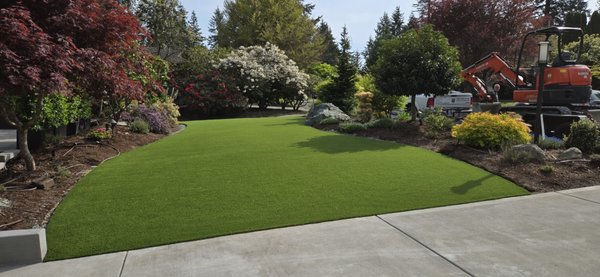 Front and Backyard - Mill Creek - This was a full front and backyard overhaul that completely redefined our clients’ outdoor living space. The project included a custom-built retaining wall to level out the sloped backyard, creating a perfect space for outdoor games and activities. In the back, we installed a professional-grade custom putting green, giving the homeowner the ultimate spot to practice short game skills right at home. The front yard got a fresh makeover too, blending low-maintenance artificial turf with clean landscaping for unbeatable curb appeal. This transformation turned unused, uneven space into a functional, fun, and stunning environment the whole family can enjoy year-round. Front and Backyard - Mill Creek - This was a full front and backyard overhaul that completely redefined our clients’ outdoor living space. The project included a custom-built retaining wall to level out the sloped backyard, creating a perfect space for outdoor games and activities. In the back, we installed a professional-grade custom putting green, giving the homeowner the ultimate spot to practice short game skills right at home. The front yard got a fresh makeover too, blending low-maintenance artificial turf with clean landscaping for unbeatable curb appeal. This transformation turned unused, uneven space into a functional, fun, and stunning environment the whole family can enjoy year-round.
