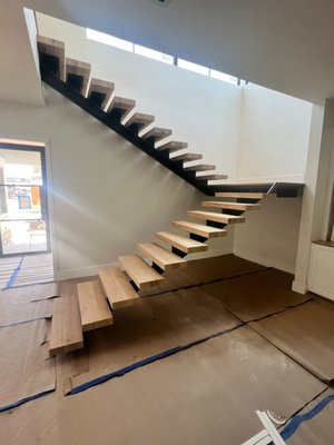 Modern Floating Staircase with Hardwood Treads - Designed and installed a sleek floating staircase featuring thick solid hardwood treads and a central steel mono-stringer frame. The open-riser design maximizes natural light throughout the room while delivering a bold, architectural feature wall effect. Engineered for stability, strength, and modern elegance. Modern Floating Staircase with Hardwood Treads - Designed and installed a sleek floating staircase featuring thick solid hardwood treads and a central steel mono-stringer frame. The open-riser design maximizes natural light throughout the room while delivering a bold, architectural feature wall effect. Engineered for stability, strength, and modern elegance.