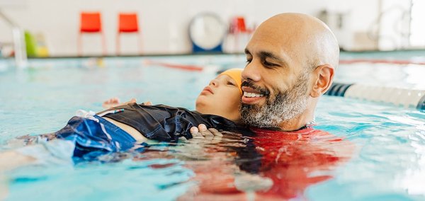 Adaptive Aquatics Program - At British Swim School, our mission is to “ensure that every person regardless of age or ability has the opportunity to become a safe and happy swimmer.” That’s why we offer a special abilities aquatics program that takes our traditional methods and places them into a specially designed program to work with swimmers of any ability, making them feel comfortable and safer in the water.
Parental involvement: Setting the stage for success
1. Discuss the instructor that will be the right fit to get the best possible results from each student. In selecting an instructor, we consider temperament, voice quality and tone, gender, personality, and any other relevant factors based on the specific needs of the swimmer.
2. Collaborate with the parent to identify the right time and location for the lessons. This decision considers noise level, light exposure, outside stimulation, time of day, and location. Our goal is to provide the best possible learning environment for each student!
3. Identify the best class level based on the abilities and goals of the swimmer. Our Dolphin 1 and Dolphin 2 class ratio can be 1:1 or 2:1 depending on the requirements and goals of each participant.
What levels do we offer?
British Swim School’s Special Abilities program is tailored to each individual student and focuses on their strengths first. We offer two levels in our Special Abilities program: Dolphin 1 and 2. These classes begin with a one-to-one ratio and may increase based on the progression of the swimmer. We recommend that each swimmer starts in a private class in order for them to become accustomed to their surroundings and to build a relationship with their instructor. Our goal is to acclimate every swimmer to our teaching methods, and, if possible, integrate the swimmer into our traditional classes when ready. Adaptive Aquatics Program - At British Swim School, our mission is to “ensure that every person regardless of age or ability has the opportunity to become a safe and happy swimmer.” That’s why we offer a special abilities aquatics program that takes our traditional methods and places them into a specially designed program to work with swimmers of any ability, making them feel comfortable and safer in the water.
Parental involvement: Setting the stage for success
1. Discuss the instructor that will be the right fit to get the best possible results from each student. In selecting an instructor, we consider temperament, voice quality and tone, gender, personality, and any other relevant factors based on the specific needs of the swimmer.
2. Collaborate with the parent to identify the right time and location for the lessons. This decision considers noise level, light exposure, outside stimulation, time of day, and location. Our goal is to provide the best possible learning environment for each student!
3. Identify the best class level based on the abilities and goals of the swimmer. Our Dolphin 1 and Dolphin 2 class ratio can be 1:1 or 2:1 depending on the requirements and goals of each participant.
What levels do we offer?
British Swim School’s Special Abilities program is tailored to each individual student and focuses on their strengths first. We offer two levels in our Special Abilities program: Dolphin 1 and 2. These classes begin with a one-to-one ratio and may increase based on the progression of the swimmer. We recommend that each swimmer starts in a private class in order for them to become accustomed to their surroundings and to build a relationship with their instructor. Our goal is to acclimate every swimmer to our teaching methods, and, if possible, integrate the swimmer into our traditional classes when ready.