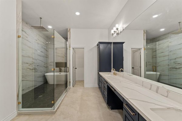 Primary Bathroom Remodel - Cleveland TX - We recently completed this luxurious bathroom remodel in Cleveland, TX, designed to bring both elegance and functionality to the space. The homeowners wanted a spa-like retreat with high-end finishes, ample storage, and a modern yet timeless design. Every detail was carefully chosen to create a space that is both beautiful and practical for daily use.
The highlight of the remodel is the oversized walk-in shower, enclosed with frameless glass and accented with gold hardware. Large-format marble-look tiles line the walls, giving a sleek and sophisticated feel, while the bold hexagon floor tiles create a striking contrast. A rainfall showerhead adds to the spa-like experience, and a built-in niche provides convenient storage for bath essentials. Positioned next to the shower, a freestanding soaking tub allows for ultimate relaxation, making this space feel like a private retreat.
The double vanity was custom-designed with deep navy cabinetry and topped with marble-style quartz countertops for a clean and polished look. Gold fixtures complement the cabinetry, adding warmth and refinement. The extended mirror reflects light beautifully, making the space feel even more open and inviting. Above the vanity, modern wall sconces provide soft, flattering lighting, perfect for getting ready in the morning.
Storage was another priority in this remodel. The custom-built walk-in closet features floor-to-ceiling shelving, hanging space, and additional compartments to keep everything organized. The deep navy finish of the cabinetry ties seamlessly into the bathroom design, maintaining a cohesive look throughout the space.
With a combination of sleek materials, warm accents, and thoughtful layout choices, this bathroom was transformed into a space that is as stunning as it is functional. The homeowners now have a place where they can unwind in style. Primary Bathroom Remodel - Cleveland TX - We recently completed this luxurious bathroom remodel in Cleveland, TX, designed to bring both elegance and functionality to the space. The homeowners wanted a spa-like retreat with high-end finishes, ample storage, and a modern yet timeless design. Every detail was carefully chosen to create a space that is both beautiful and practical for daily use.
The highlight of the remodel is the oversized walk-in shower, enclosed with frameless glass and accented with gold hardware. Large-format marble-look tiles line the walls, giving a sleek and sophisticated feel, while the bold hexagon floor tiles create a striking contrast. A rainfall showerhead adds to the spa-like experience, and a built-in niche provides convenient storage for bath essentials. Positioned next to the shower, a freestanding soaking tub allows for ultimate relaxation, making this space feel like a private retreat.
The double vanity was custom-designed with deep navy cabinetry and topped with marble-style quartz countertops for a clean and polished look. Gold fixtures complement the cabinetry, adding warmth and refinement. The extended mirror reflects light beautifully, making the space feel even more open and inviting. Above the vanity, modern wall sconces provide soft, flattering lighting, perfect for getting ready in the morning.
Storage was another priority in this remodel. The custom-built walk-in closet features floor-to-ceiling shelving, hanging space, and additional compartments to keep everything organized. The deep navy finish of the cabinetry ties seamlessly into the bathroom design, maintaining a cohesive look throughout the space.
With a combination of sleek materials, warm accents, and thoughtful layout choices, this bathroom was transformed into a space that is as stunning as it is functional. The homeowners now have a place where they can unwind in style.