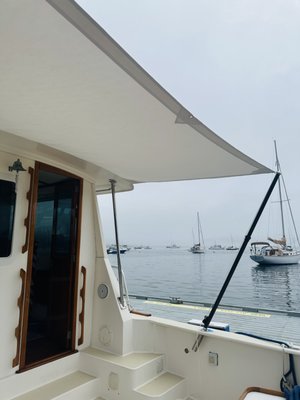 Custom Sunbrella Aft Awning for a Bruckmann 36.6 - Our customer wanted sun and rain protection on the aft deck of a Bruckmann 36.6. We designed and fabricated a custom Sunbrella aft awning that is easily installed and removed via a zippered keder track and two Tele-Sun Carbon Fiber Marine Shade poles. Key features are included below:
- Oyster Sunbrella Marine Canvas
- reinforced corners
- zippered keder strip with velcro rain
flap at FWD end
- aft corners tensioned to carbon fiber
poles
- drainage tie-down grommet at center
aft edge
- 2 Tele-Sun Carbon Fiber Marine Shade
Poles with Carrying Bag (adjustable 52"
to 80"
- 3/16" poly line with brass snaps Custom Sunbrella Aft Awning for a Bruckmann 36.6 - Our customer wanted sun and rain protection on the aft deck of a Bruckmann 36.6. We designed and fabricated a custom Sunbrella aft awning that is easily installed and removed via a zippered keder track and two Tele-Sun Carbon Fiber Marine Shade poles. Key features are included below:
- Oyster Sunbrella Marine Canvas
- reinforced corners
- zippered keder strip with velcro rain
flap at FWD end
- aft corners tensioned to carbon fiber
poles
- drainage tie-down grommet at center
aft edge
- 2 Tele-Sun Carbon Fiber Marine Shade
Poles with Carrying Bag (adjustable 52"
to 80"
- 3/16" poly line with brass snaps