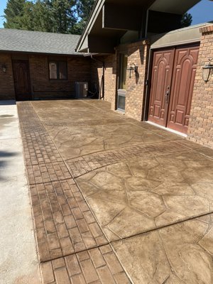 Brick pattern border with flagstone stamped concrete - This patio entryway was done in Keenseburg Colorado. The homeowner wanted brick pattern border and we came up with the design for the look and decided to do a flagstone pattern in between. We poured the concrete with the color in and then antiqued it to blend in the 2 separate pours to give it a natural look. The sealer enhanced the color and gave it a nice shine without making the surface too slick when wet. We are proud of this project and design.