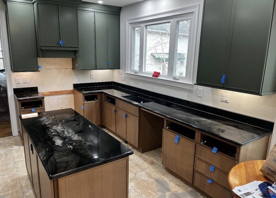 Scandalous Black Quartzite - Striking kitchen featuring Scandalous Black Quartzite countertops paired with earthy green upper cabinets and rich brown lowers. The natural tones come together for a bold yet grounded, organic feel. Scandalous Black Quartzite - Striking kitchen featuring Scandalous Black Quartzite countertops paired with earthy green upper cabinets and rich brown lowers. The natural tones come together for a bold yet grounded, organic feel.
