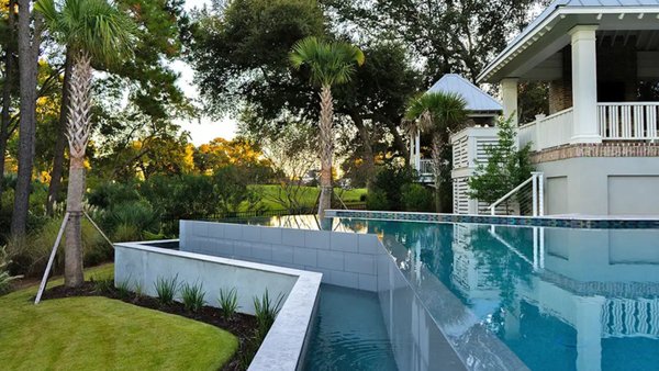 Elevated Elegance: A Modern Infinity Pool Design - This luxurious backyard pool design combines contemporary style with thoughtful functionality. The custom-shaped infinity pool features a sleek overflow edge that seamlessly blends the pool's reflective surface with the surrounding landscape. The elevated design creates a captivating visual effect while maximizing views of the lush outdoor scenery. A cozy spa is integrated into the layout, adding a relaxing retreat space. The spacious deck, adorned with sophisticated stone tiles, offers ample room for lounging and entertaining. Together, these elements provide a harmonious balance of modern aesthetics and outdoor comfort. Elevated Elegance: A Modern Infinity Pool Design - This luxurious backyard pool design combines contemporary style with thoughtful functionality. The custom-shaped infinity pool features a sleek overflow edge that seamlessly blends the pool's reflective surface with the surrounding landscape. The elevated design creates a captivating visual effect while maximizing views of the lush outdoor scenery. A cozy spa is integrated into the layout, adding a relaxing retreat space. The spacious deck, adorned with sophisticated stone tiles, offers ample room for lounging and entertaining. Together, these elements provide a harmonious balance of modern aesthetics and outdoor comfort.