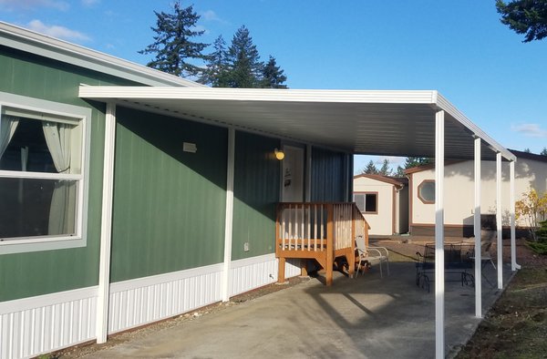 Carport for Manufactured Home - Most manufactured homes do not have foundations, so adding a regular wall mounted carport can be risky.  If you live near trees, patio covers and carports will gather leaves and pineneedles, then get wet and then add more layers, and if not cleaned off, they can become very heavy!  Sometimes, even in the South, snow can contribute to the problem. (snow on your cover becomes a large spounge that gathers all of the rain that follows)  For these reasons and many others, this cover requires inside posts making it a "Free Standing" carport.  We still attach the structure to the house and seal it, but the wall is not suporting the cover.  Conecting to the house also keeps the free standing carport from swaying.
The wise man built his carport on the Rock... which means including inside posts in this case.