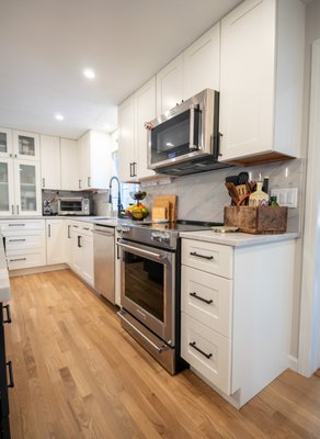 Full Kitchen remodel - Full kitchen renovation featuring premium cabinetry, quartz countertops, full-height backsplash, and designer hardware. The mix of white perimeter cabinets and a bold dark island created a refined, high-end look with practical everyday function Full Kitchen remodel - Full kitchen renovation featuring premium cabinetry, quartz countertops, full-height backsplash, and designer hardware. The mix of white perimeter cabinets and a bold dark island created a refined, high-end look with practical everyday function