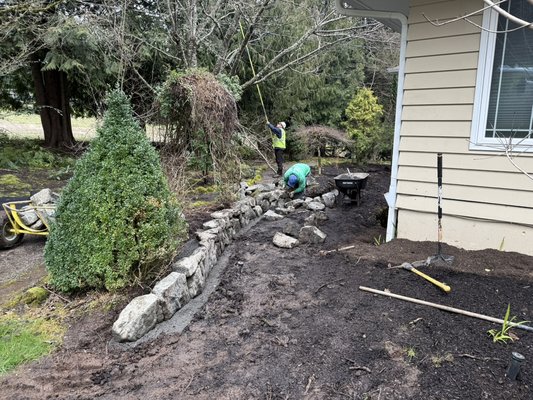 Retaining wall - We built a retaining wall about 40-50 ft long of rocks put into this wall we dug out the line and put gravel at the bottom to hold the rock into place and as went along we filled in the back with gravel as well Retaining wall - We built a retaining wall about 40-50 ft long of rocks put into this wall we dug out the line and put gravel at the bottom to hold the rock into place and as went along we filled in the back with gravel as well