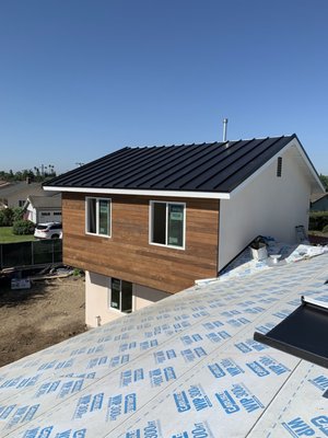 Oleander - Modern Standing Seam Metal Roof Installation at Oleander. This project features durable 24ga Galvalume metal with a sleek Kynar finish in black. Our team expertly fabricated and installed the panels to ensure a seamless and weather-resistant roof that enhances the home's aesthetic and provides long-lasting protection.