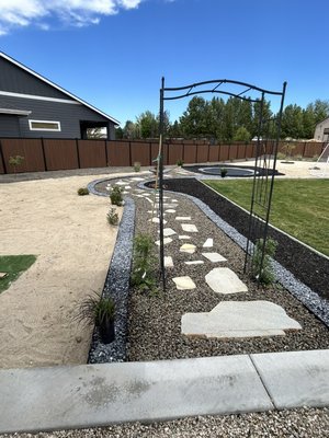 Flagstone stepping stones surrounded by black and tan rock surrounded by black metal border, sand, and black mulch.  - We ended up custom creating a Flagstone pathway that leads into an inground trampoline. Trampoline is surrounded by play recycled, rubber, mulch, that we glued down with a rubber border surrounding it we use the decorative pearl blue rock, metal border, dividing each rock and the pathway . The path was a custom design from everyone here at C&S Rustic Contractors LLC . We are more than pleased how it turned out . we put a lot of time and effort into this job for our client and his family . he is one of our our Weekly lawn care maintenance clients so we were more than happy to take on the job . Him and his family are very grateful and love the finish product. We still have a couple minor finishing touches we would like to do, but overall, we are very pleased and blessed to have the opportunity to create a magical outdoor space for Phillip and his family . I think our favorite part would be the playground recycled, rubber mulch around the inground trampoline that we glued down so no matter what kind of weather ! Contact us for an outdoor custom creation today !! Flagstone stepping stones surrounded by black and tan rock surrounded by black metal border, sand, and black mulch.  - We ended up custom creating a Flagstone pathway that leads into an inground trampoline. Trampoline is surrounded by play recycled, rubber, mulch, that we glued down with a rubber border surrounding it we use the decorative pearl blue rock, metal border, dividing each rock and the pathway . The path was a custom design from everyone here at C&S Rustic Contractors LLC . We are more than pleased how it turned out . we put a lot of time and effort into this job for our client and his family . he is one of our our Weekly lawn care maintenance clients so we were more than happy to take on the job . Him and his family are very grateful and love the finish product. We still have a couple minor finishing touches we would like to do, but overall, we are very pleased and blessed to have the opportunity to create a magical outdoor space for Phillip and his family . I think our favorite part would be the playground recycled, rubber mulch around the inground trampoline that we glued down so no matter what kind of weather ! Contact us for an outdoor custom creation today !!
