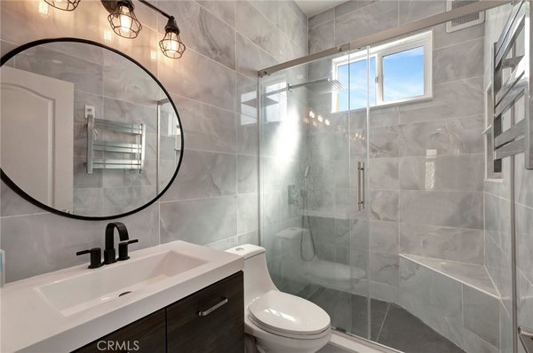 Bathroom Remodel - This bathroom was completely remodeled from a dated, builder-grade design into a sleek, modern retreat. The original space featured a traditional tub-and-shower combo with frosted glass sliders, basic fixtures, and a white laminate vanity. We reimagined the layout with a walk-in glass-enclosed shower featuring large-format marble-look tiles and a rainfall showerhead. The vanity was upgraded to a modern unit with clean lines, matte black fixtures, and a vessel sink. The lighting was replaced with industrial-style sconces for a bold, contemporary touch, and a round mirror was added to soften the geometric aesthetic. Every detail—from the wall tiles to the flooring and hardware—was carefully selected to create a luxurious and functional space. Bathroom Remodel - This bathroom was completely remodeled from a dated, builder-grade design into a sleek, modern retreat. The original space featured a traditional tub-and-shower combo with frosted glass sliders, basic fixtures, and a white laminate vanity. We reimagined the layout with a walk-in glass-enclosed shower featuring large-format marble-look tiles and a rainfall showerhead. The vanity was upgraded to a modern unit with clean lines, matte black fixtures, and a vessel sink. The lighting was replaced with industrial-style sconces for a bold, contemporary touch, and a round mirror was added to soften the geometric aesthetic. Every detail—from the wall tiles to the flooring and hardware—was carefully selected to create a luxurious and functional space.