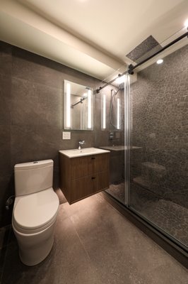 Upper West Side Kitchen and Bathroom Remodel - The finished renovation brings together warmth and contrast in all the right ways. The kitchen feels woodsy yet refined, with clean lines, natural textures, and a bright, open layout that keeps the space feeling fresh and inviting. In contrast, the bathroom embraces a darker, moodier palette layered with rich stone tiles and bold finishes that create a sophisticated, spa like retreat. Together, the spaces balance organic warmth with modern edge.