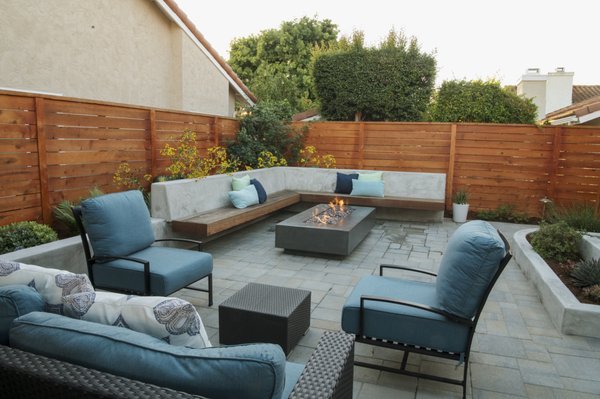 A Warm, Modern Outdoor Makeover - This home received a full front and backyard transformation designed to bring beauty, comfort, and effortless outdoor living to everyday life. The goal was simple: create inviting spaces the homeowners could enjoy from morning coffee to evening gatherings with friends.

A Front Yard That Welcomes You In
The entry was completely reimagined to feel warm and welcoming. A handcrafted cedar fence surrounds the front yard, adding privacy without feeling closed off. Clean concrete stepping pads guide you to the front door, with soft river rock adding a natural touch between each step.

Fresh, vibrant plantings bring the space to life—lush greens, soft textures, and a statement ceramic pot that gives the front yard a pop of interest. The result feels friendly, bright, and beautifully connected to the home.

Your Backyard, Reimagined
The backyard was designed to be an everyday retreat. A custom concrete and floating wood bench wraps around a modern fire feature, creating the perfect spot to unwind, gather, and enjoy the glow of a fire year-round.

A covered outdoor kitchen and dining area extend the home’s living space, making outdoor cooking and entertaining effortless. The open layout gives the backyard multiple zones to relax—whether it’s lounging with family, hosting dinner, or enjoying a quiet evening outdoors.

Beautiful. Comfortable. Built to Last.
Warm cedar fencing, durable paver flooring, and thoughtfully chosen plants come together to create a space that’s as functional as it is beautiful. Soft lighting adds warmth at night, turning the entire yard into a cozy, welcoming environment.

This project shows how a well-designed landscape can change the way you live at home—bringing more joy, more connection, and more time spent outdoors.