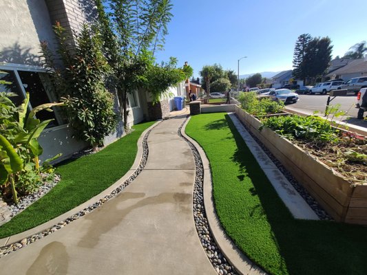 Concrete Turf - This remodel was done during the pandemic in the city of Simi Valley. We were able to create a nice pathway in front of the house with a unique design. We were able to incorporate 3 elements river rocks, turf and concrete. Our customer couldn't decide what to use. We were able to create a combination of 3 elements and they were extremely happy with the results. In the side path they had an open space where they wanted a sitting area. We were able to create this by adding a paver walkway with a custom made fire pit!