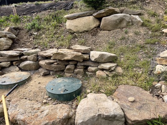 Rock wall Landscaping - Needed to keep the dirt from running down hill onto the septic tank lids. So the landscape was the best solution .