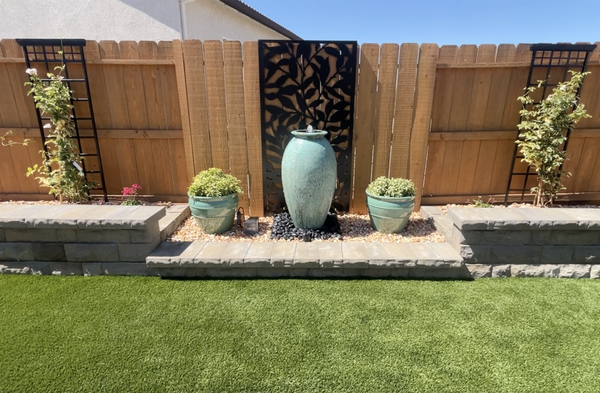 Roseville New Development - This project was designed by the homeowners. We installed a putting green, concrete walkways and patio, artificial turf, a raised concrete patio, rock mulch, and a decorative wall to highlight their water feature.