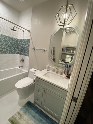Kid's Bath Remodel - This remodel was done on a kid's bathroom that was in need of a sit down vanity for the client's daughter. They also needed a soaking tub and a more functional shower. In order to maximize storage and create the vanity, we removed the built-in linen closet and placed a make-up vanity in it's place. The builder grade tub was removed and replaced with a deep soaking tub and finished off with beautiful raised subway tile with a colorful accent. We painted the existing vanity sink base and added decorative hardware, quartz countertops, new sink and faucet, a matching wood mirror and a decorative pendant. The finished product is a beautiful bathroom perfect for a teenage girl!