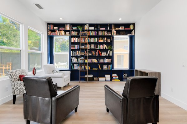 Custom Library Room Addition by Pro Builders and Design in La Costa, CA - At Pro Builders and Design, we approached this library room addition in La Costa with a clear layout and material direction. The homeonwers needed more than storage, they wanted a space that felt rooted, balanced, and intentionally set apart from the rest of the home.
We started with a full-height built-in wall system finished in a deep navy satin lacquer. The cabinetry was designed with adjustable shelving up top, flat panel doors with soft-close hardware below, and integrated display cubbies for flexibility. Framing the design are two inset windows, which we intentionally left trimless to keep the built-in wall feeling clean and architectural. A black metal rolling ladder adds functionality without breaking up the visual structure of the wall.
We kept the surrounding walls crisp white to reflect natural light from the corner windows. For continuity, we extended the wide plank engineered wood flooring from the rest of the home. Its warm tone grounding the cool palette of the shelving. Brass hardware and matching ladder rails introduce a subtle metal contrast that reads quietly against the darker cabinetry.
A round wood table sits centered in the space, chosen for its soft edges and proportion. It works equally well as a reading surface or casual workspace without disrupting circulation. We finished the room with flush LED lighting and wall outlets tucked just below shelving lines, practical, but discreet.
Every material and layout decision was based on real daily use: lighting, reachability, storage depth, and flow. Nothing added for show. Nothing left unfinished.
If you're thinking about adding a space with clear intent and long-term usefulness, Pro Builders and Design, can help you build it right from the start. Custom Library Room Addition by Pro Builders and Design in La Costa, CA - At Pro Builders and Design, we approached this library room addition in La Costa with a clear layout and material direction. The homeonwers needed more than storage, they wanted a space that felt rooted, balanced, and intentionally set apart from the rest of the home.
We started with a full-height built-in wall system finished in a deep navy satin lacquer. The cabinetry was designed with adjustable shelving up top, flat panel doors with soft-close hardware below, and integrated display cubbies for flexibility. Framing the design are two inset windows, which we intentionally left trimless to keep the built-in wall feeling clean and architectural. A black metal rolling ladder adds functionality without breaking up the visual structure of the wall.
We kept the surrounding walls crisp white to reflect natural light from the corner windows. For continuity, we extended the wide plank engineered wood flooring from the rest of the home. Its warm tone grounding the cool palette of the shelving. Brass hardware and matching ladder rails introduce a subtle metal contrast that reads quietly against the darker cabinetry.
A round wood table sits centered in the space, chosen for its soft edges and proportion. It works equally well as a reading surface or casual workspace without disrupting circulation. We finished the room with flush LED lighting and wall outlets tucked just below shelving lines, practical, but discreet.
Every material and layout decision was based on real daily use: lighting, reachability, storage depth, and flow. Nothing added for show. Nothing left unfinished.
If you're thinking about adding a space with clear intent and long-term usefulness, Pro Builders and Design, can help you build it right from the start.