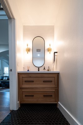 Half Bathroom Remodel - This half-bathroom was once an afterthought—plain, outdated, and uninspiring. But the homeowners wanted something different—a space that would impress their guests from the moment they walked in.  

We brought their vision to life with warm wood textures, sleek black hardware, and gold accents for a touch of elegance. The white quartz countertop keeps it fresh and bright, while the bold black hex flooring adds a modern edge. Now, this isn’t just a guest bathroom—it’s a conversation starter.  

A small space with a big impact. Because even guests deserve a little luxury!