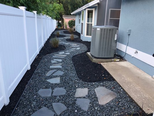 Relandscape with Grey Rock and Black Mulch - This property was overgrown and the landscaping did not match the new color for the house. In addition to trimming and removing all of the overgrown and volunteer plant material, we installed new plants, rock, mulch, sod, and even designed unique walkways along the sides of the property that adds a beautiful and functional feature to the home that also compliments the new color palette. Our customer loves their new yard and we continue to provide quarterly cleanups for them! Relandscape with Grey Rock and Black Mulch - This property was overgrown and the landscaping did not match the new color for the house. In addition to trimming and removing all of the overgrown and volunteer plant material, we installed new plants, rock, mulch, sod, and even designed unique walkways along the sides of the property that adds a beautiful and functional feature to the home that also compliments the new color palette. Our customer loves their new yard and we continue to provide quarterly cleanups for them!