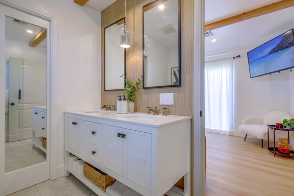 Anaheim Remodel - Although kept in great condition, the new homeowners felt that the home was not particularly their style. This project entailed demoing a dividing wall from the kitchen and living room, installing and hiding a large beam in the ceiling, installing recessed lights throughout, painting the entire home, converting a den to a primary suite and completely remodeling all the bathrooms and kitchen. The color palette for this home was white, white oak and black. All the walls in the home were painted a beautiful Chantilly Lace from Benjamin Moore which looked stunning next to the white oak flooring. The kitchen has a 9’ island that can entertain all your guests, even the cats, who now have a place for dinner & drinks (check out the kitty section in the images below). The client did not shy away from bold patterns, and opted for the textured pleated tile for the fireplace, a chevron black and white tile for a powder room accent wall, penny tile for the secondary bathroom and a wood look fluted porcelain tile for the primary bathroom. Anaheim Remodel - Although kept in great condition, the new homeowners felt that the home was not particularly their style. This project entailed demoing a dividing wall from the kitchen and living room, installing and hiding a large beam in the ceiling, installing recessed lights throughout, painting the entire home, converting a den to a primary suite and completely remodeling all the bathrooms and kitchen. The color palette for this home was white, white oak and black. All the walls in the home were painted a beautiful Chantilly Lace from Benjamin Moore which looked stunning next to the white oak flooring. The kitchen has a 9’ island that can entertain all your guests, even the cats, who now have a place for dinner & drinks (check out the kitty section in the images below). The client did not shy away from bold patterns, and opted for the textured pleated tile for the fireplace, a chevron black and white tile for a powder room accent wall, penny tile for the secondary bathroom and a wood look fluted porcelain tile for the primary bathroom.