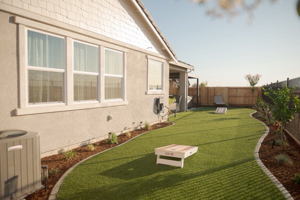 Project 5 - Feast your eyes on a space that truly maximizes every square foot without feeling crowded. This backyard was designed to take limited usable space and turn it into a clean, functional, and visually balanced retreat. The low-maintenance artificial lawn anchors the yard, providing year-round greenery while surrounding planting beds introduce warmth and contrast.
This layout is ideal for busy individuals, couples, or families who want a polished outdoor environment without dedicating their weekends to constant upkeep. It’s clean, efficient, and built to stay that way.
That said, I always keep it real — artificial turf does come with tradeoffs. Because it’s a synthetic surface with no moisture retained between blades, it can heat up significantly during Sacramento summers. Strategic planning is everything. Proper tree placement and future canopy coverage can dramatically improve comfort and long-term usability. When you think ahead, you set the yard up for success.
The side yards weren’t treated as leftover space — they were designed with intention. One side features a well-manicured stepping-stone path that creates a smooth, inviting transition from front to back. The other side serves as a rock garden, bringing texture and a grounded, natural feel that balances the modern turf area.
To finish it off, we incorporated trellises to add vertical interest and soften the fencing. The homeowner secured them to the fence using 1x1 lumber cleats — a simple but smart detail that reinforced stability while keeping everything clean and flush. I appreciated that moment; it was a small adjustment that taught me something new and reminded me that even simple techniques can elevate the final result. Trailing vines were planted to mature over time, bringing movement and life into the vertical plane.
This project blends practicality with design — clean lines, low maintenance, thoughtful plant placement, and long-term vision — all working together to create an outdoor space that’s both usable and refined. Project 5 - Feast your eyes on a space that truly maximizes every square foot without feeling crowded. This backyard was designed to take limited usable space and turn it into a clean, functional, and visually balanced retreat. The low-maintenance artificial lawn anchors the yard, providing year-round greenery while surrounding planting beds introduce warmth and contrast.
This layout is ideal for busy individuals, couples, or families who want a polished outdoor environment without dedicating their weekends to constant upkeep. It’s clean, efficient, and built to stay that way.
That said, I always keep it real — artificial turf does come with tradeoffs. Because it’s a synthetic surface with no moisture retained between blades, it can heat up significantly during Sacramento summers. Strategic planning is everything. Proper tree placement and future canopy coverage can dramatically improve comfort and long-term usability. When you think ahead, you set the yard up for success.
The side yards weren’t treated as leftover space — they were designed with intention. One side features a well-manicured stepping-stone path that creates a smooth, inviting transition from front to back. The other side serves as a rock garden, bringing texture and a grounded, natural feel that balances the modern turf area.
To finish it off, we incorporated trellises to add vertical interest and soften the fencing. The homeowner secured them to the fence using 1x1 lumber cleats — a simple but smart detail that reinforced stability while keeping everything clean and flush. I appreciated that moment; it was a small adjustment that taught me something new and reminded me that even simple techniques can elevate the final result. Trailing vines were planted to mature over time, bringing movement and life into the vertical plane.
This project blends practicality with design — clean lines, low maintenance, thoughtful plant placement, and long-term vision — all working together to create an outdoor space that’s both usable and refined.