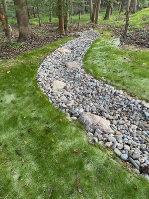 Swales - Managing water runoff is crucial for preventing erosion and protecting your property. Swales help by directing excess water away from structures and landscaping, allowing it to absorb naturally into the ground. Using materials like River Jack Stones or Rip Rap Stones enhances durability and creates a visually appealing solution. Swales - Managing water runoff is crucial for preventing erosion and protecting your property. Swales help by directing excess water away from structures and landscaping, allowing it to absorb naturally into the ground. Using materials like River Jack Stones or Rip Rap Stones enhances durability and creates a visually appealing solution.