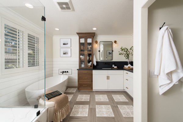 Master Bathroom Remodel in Ladera Ranch with Modern Farmhouse Design - One of the most exciting aspects of remodeling in Orange County is the fact that every design and every project is different. From luxurious master baths to seaside kitchen remodels and more, we do it all and we love the unique qualities of each renovation.

This master bathroom remodel in Ladera Ranch is no exception. It’s full of contrasting features that all contribute to a farmhouse feel with a modern look. A dark quartz countertop and backsplash, which could easily be taken as soapstone, boldly contrasts with the white vanity cabinetry while gold pulls and fixtures make the design pop.

Across the room, black fixtures and a black linear drain stand out nicely against the white porcelain tiles of the shower. And, don’t forget about this walk in shower’s custom features - a built in shower bench and shampoo niche which provide storage for bath accessories and also a place to sit while showering.

Adjacent to the shower is a beautiful freestanding tub. It’s not hard to get the farmhouse feel in this part of the room with the walls behind the tub being lined with shiplap about halfway up each wall.

At Sea Pointe Design & Remodel, we’re committed to bringing you the best remodeling experience - expert craftsmanship, award-winning design, and quality materials to create a space that you and your family will enjoy for years to come. Ready to plan your bathroom remodel? Simply give us a call at (949) 861-3400 to schedule your complimentary design consultation.