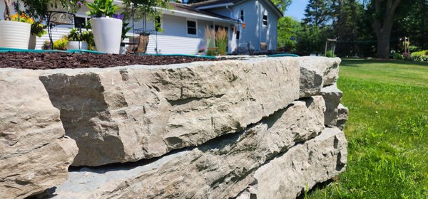 Outcropping Walls - Outcroppings consist of large  natural limestone in many colors, weighing approx 1,000 lbs each. These stones can only be placed by machinery into layers.  This type of rock and wall is more sturdy.

Retaining walls consist of manufactured blocks that come in a larger variety of colors than outcroppings do.  These blocks can weigh approximately 60+ pounds each and typically placed by hand.  These blocks are interlocking and stacked on top of one another.

No matter which you decide to go with, both are used to hold back earth where there is an abrupt change in soil height, allows for more usable space, and prevents erosion.  Both will add beauty to your landscape and value to your home or business.

Check out our website for more project photos and make sure to fill out our contact form so we can discuss how a new wall can transform your landscape!

Www.foxvalleylandscaping.net