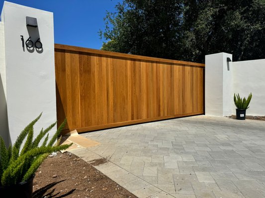 Sliding Gate with Opener - Crafted from premium white oak, this sliding gate combines natural elegance with durability. Featuring a smooth-glide track system and sealed with a weather-resistant clear coat, it offers timeless style and reliable performance for any property. Optional metal accents and custom finishes available. Sliding Gate with Opener - Crafted from premium white oak, this sliding gate combines natural elegance with durability. Featuring a smooth-glide track system and sealed with a weather-resistant clear coat, it offers timeless style and reliable performance for any property. Optional metal accents and custom finishes available.