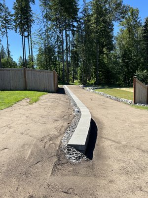 Retaining wall, grading and drainage. - We installed a retaining wall to raise the level of the homeowners side yard and to eliminate the sloped yard allowing for easier maintenance and access. We also installed drainage behind the wall to eliminate the water pooling in the yard. Retaining wall, grading and drainage. - We installed a retaining wall to raise the level of the homeowners side yard and to eliminate the sloped yard allowing for easier maintenance and access. We also installed drainage behind the wall to eliminate the water pooling in the yard.