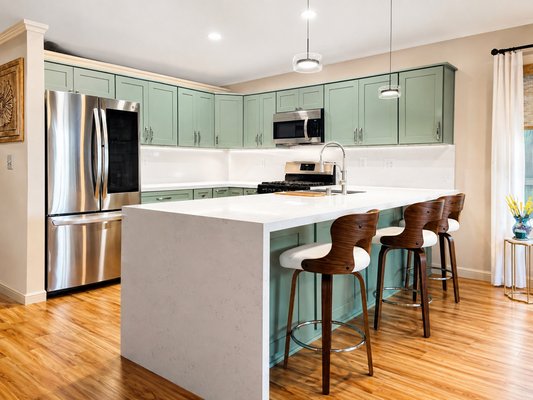 Modern Kitchen Remodel | Modesto, CA - This kitchen was completely transformed with a fresh, modern design while maintaining a warm and inviting feel. We installed sage green shaker cabinets, bright white quartz countertops with a waterfall island, a full-height backsplash, updated hardware, and stainless steel appliances to create a clean, timeless look. The new layout provides more workspace, improved storage, and a beautiful gathering space for family and friends. From demolition to the final details, every aspect of this remodel was completed with quality craftsmanship, leaving the homeowners with a kitchen they love spending time in.