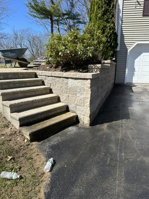 Retaining wall and stairs in Westminster MA - We transformed an old wooden retaining wall into a stunning retaining wall with stairs using the beautiful Vineyard Blend material. The project involved complete removal of the old wall, followed by meticulous excavation and the addition of crushed stone for a solid base. Then, I carefully laid the Vineyard Blend blocks, ensuring they were perfectly leveled for a flawless appearance and lasting functionality. Additionally, I installed caps on the top of the wall for a sleek and durable finish. Upon completion, we added quality soil and seed grass and thoroughly cleaned the area, leaving behind a beautifully integrated project.