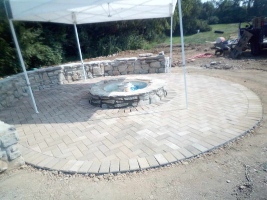 Concrete footer with stone wall paired with paver patio and stone fire pit. - This was new construction added to a house in Indian hill. 
The fire pit has a gas line running to it just in case the client prefers gas over wood.
