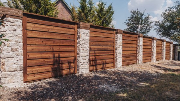 Horizontal Cedar Fence w/ Austin Stone Columns - 8 foot tall horizontal board-on-board pre-stained cedar fence with austin stone columns installed in Heath, Texas.