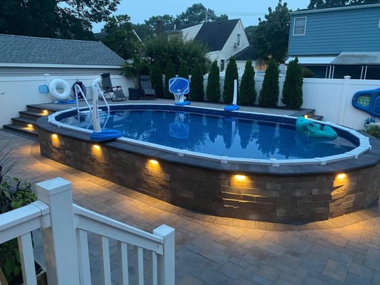 New Backyard Oasis - We gave this Massapequa Park home a new backyard OASIS. On this project we did a complete pool surround, we used Cambridge Toffe Onyx Old English block around the pool , which was also used for the raised backside landing with two entries into the pool. The two steps leading into the pool were made from Cambridge Toffee Onyx Old English block with Coal bullnose which was also used for the capping around the pool. The same materials were used for the outdoor kitchen as well, with a beautiful granite top.All the pavers were Cambridge Toffee Onyx 3pc Ledgstone with 6x9 Coal borders. We also added our signature outdoor lighting around the pool and kitchen, after all job was completed we added slate polymeric sand to all the paver joints. New Backyard Oasis - We gave this Massapequa Park home a new backyard OASIS. On this project we did a complete pool surround, we used Cambridge Toffe Onyx Old English block around the pool , which was also used for the raised backside landing with two entries into the pool. The two steps leading into the pool were made from Cambridge Toffee Onyx Old English block with Coal bullnose which was also used for the capping around the pool. The same materials were used for the outdoor kitchen as well, with a beautiful granite top.All the pavers were Cambridge Toffee Onyx 3pc Ledgstone with 6x9 Coal borders. We also added our signature outdoor lighting around the pool and kitchen, after all job was completed we added slate polymeric sand to all the paver joints.